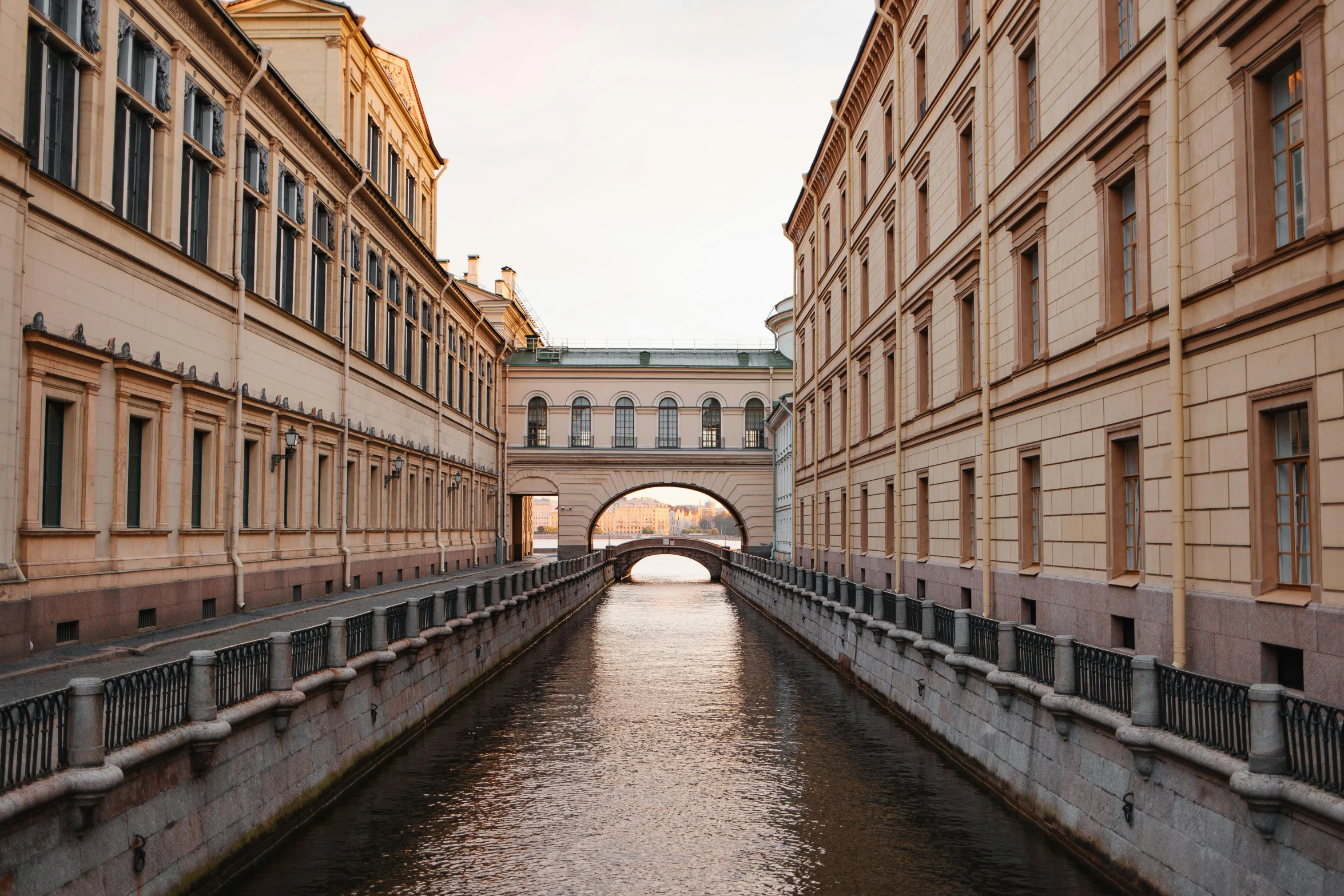 a river running through a city next to tall buildings, inspired by Anna Füssli, pexels contest winner, neoclassicism, there are archways, saint petersburg, in the style wes anderson, moat