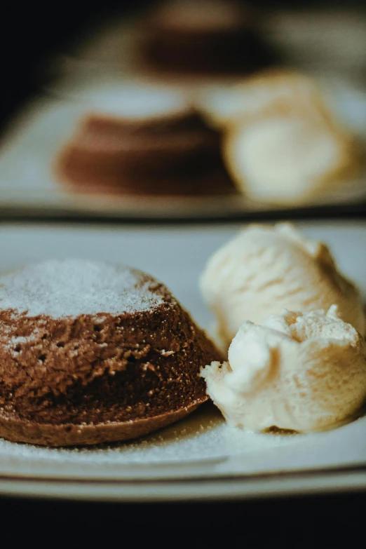 a couple of desserts sitting on top of a white plate, by Lee Loughridge, unsplash, molten, powder, brown:-2, ice cream on the side