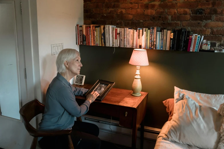 a woman sitting at a desk reading a book, a portrait, by Everett Warner, pexels contest winner, someone in home sits in bed, profile image, old apartment, integrating with technology