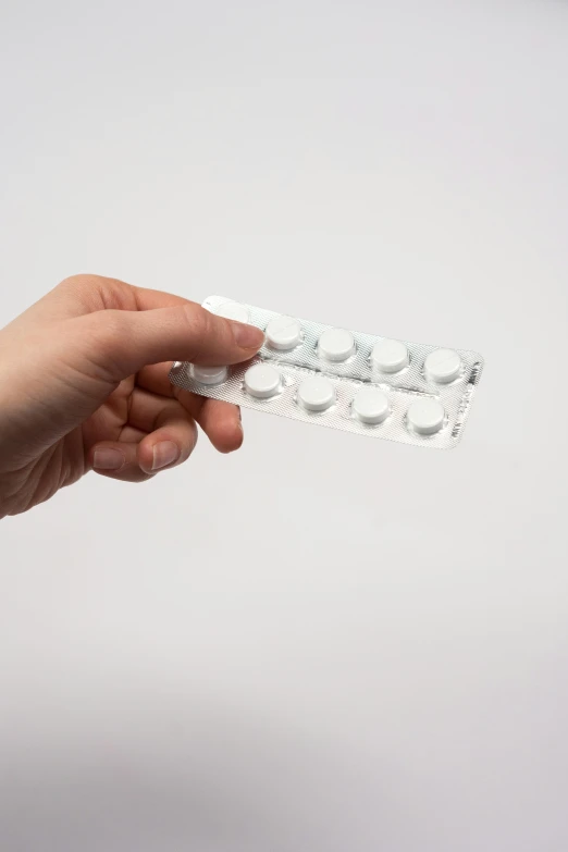 a person holding a pill pack in their hand, by Adam Marczyński, plasticien, on white paper, lined up horizontally, very round, replica model