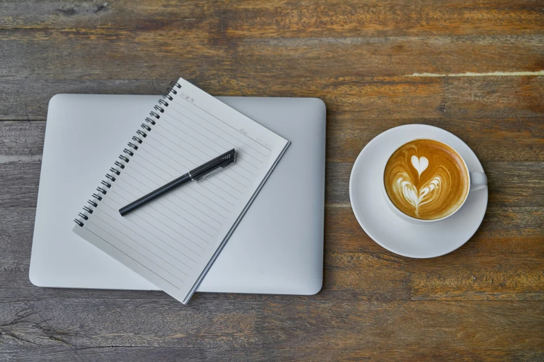 a cup of coffee and a notebook on a wooden table, by Carey Morris, unsplash contest winner, computer art, 9 9 designs, laptops, scribbled lines, bottom angle