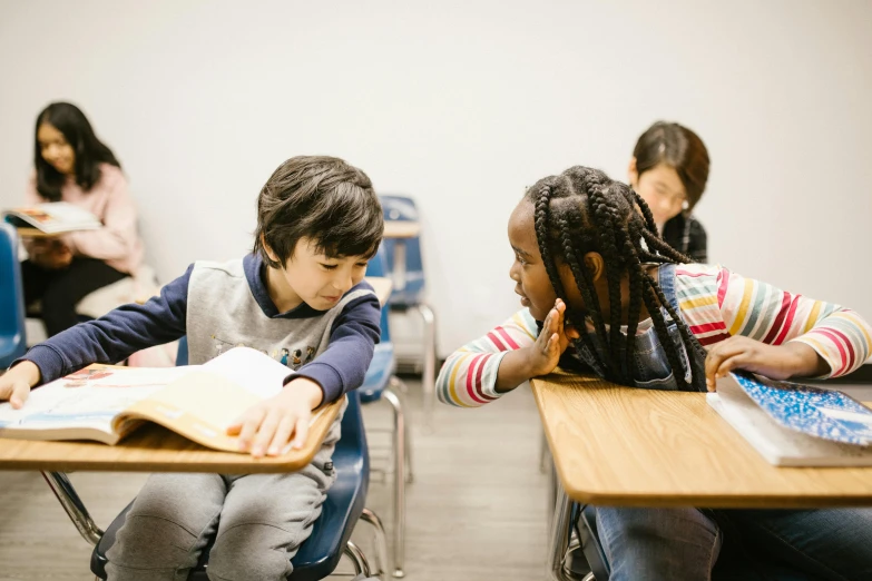 a group of children sitting at desks in a classroom, by Kiyohara Tama, pexels contest winner, reaching out to each other, ayami kojima and lyde caldwell, facing each other, brandywine school