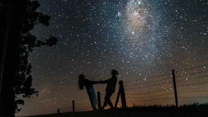 a couple of people that are standing in the grass, pexels contest winner, conceptual art, sky full of stars, twinkling and spiral nubela, southern cross, taken in the late 2010s