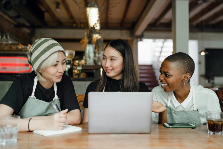 three women sitting at a table looking at a laptop, trending on pexels, aussie baristas, avatar image, asian descent, in a workshop