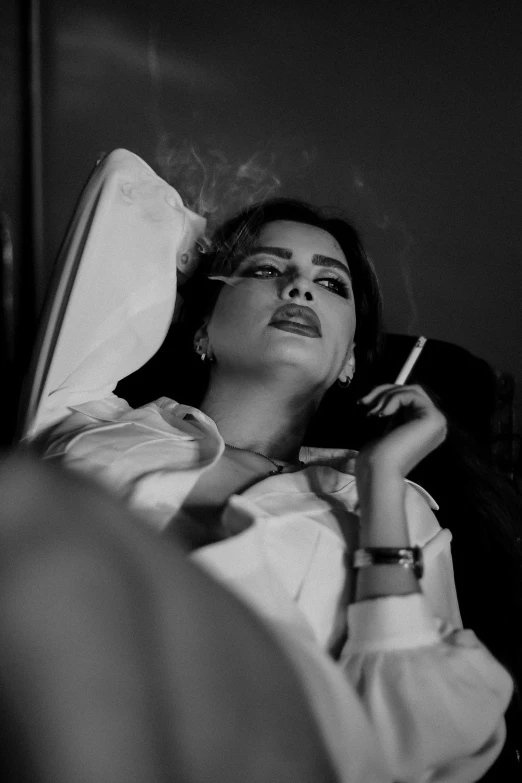 a woman laying in bed with a cigarette in her mouth, a black and white photo, pexels contest winner, aestheticism, photo of penelope cruz, ☁🌪🌙👩🏾, provocative indian, music video