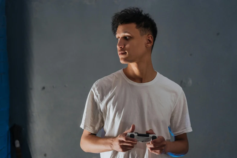 a young man holding a video game controller, by Adam Marczyński, pexels contest winner, dressed in a white t-shirt, avatar image, asian male, non binary model