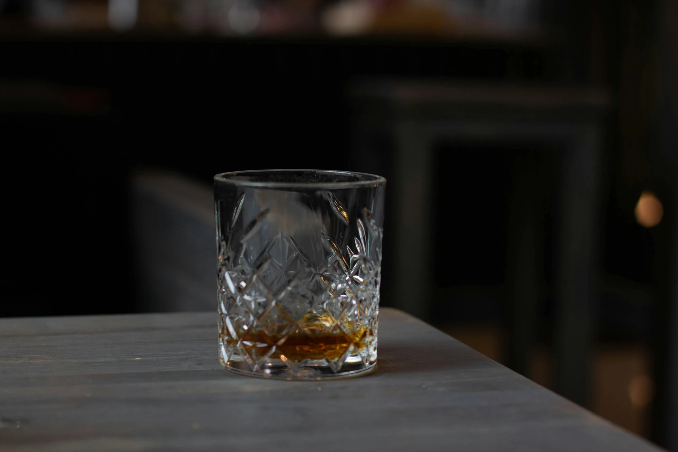 a glass of whiskey sitting on top of a wooden table, unsplash, photorealism, hd footage, multiple stories, faceted, glasgow