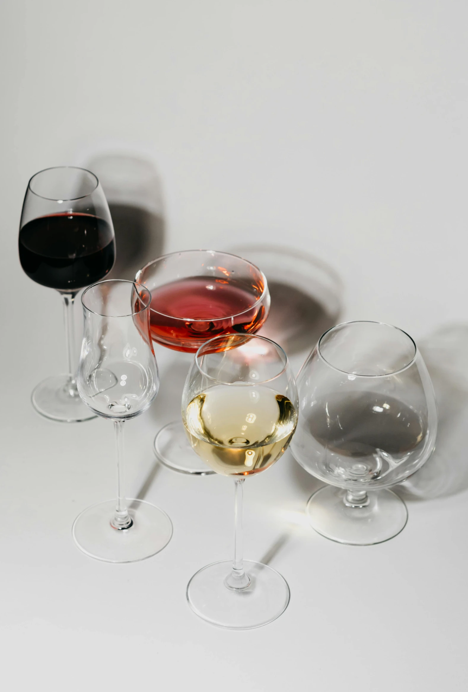 a group of wine glasses sitting next to each other, plain background, multiple stories, collection product, glassware