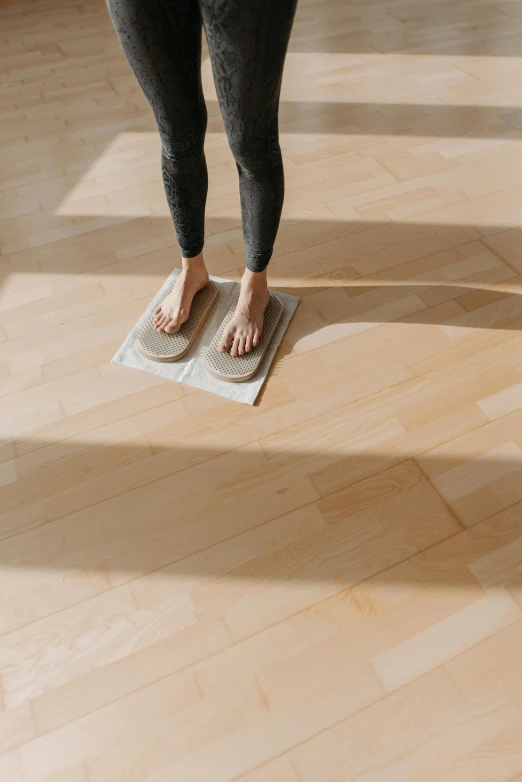 a woman standing on a scale in a room, sustainable materials, foot wraps, meditative, square