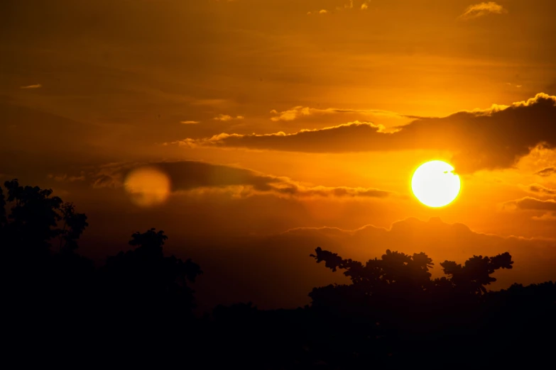 the sun is setting behind some trees, pexels contest winner, jamaica, orange yellow ethereal, solar eclipse in the sky, mount