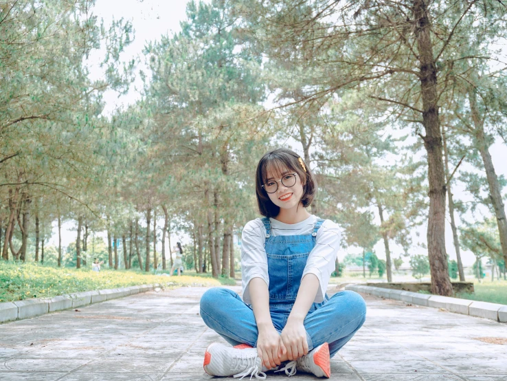 a woman sitting on a skateboard in a park, inspired by Kim Jeong-hui, pexels contest winner, wearing blue jean overalls, avatar image, ulzzang, cute slightly nerdy smile