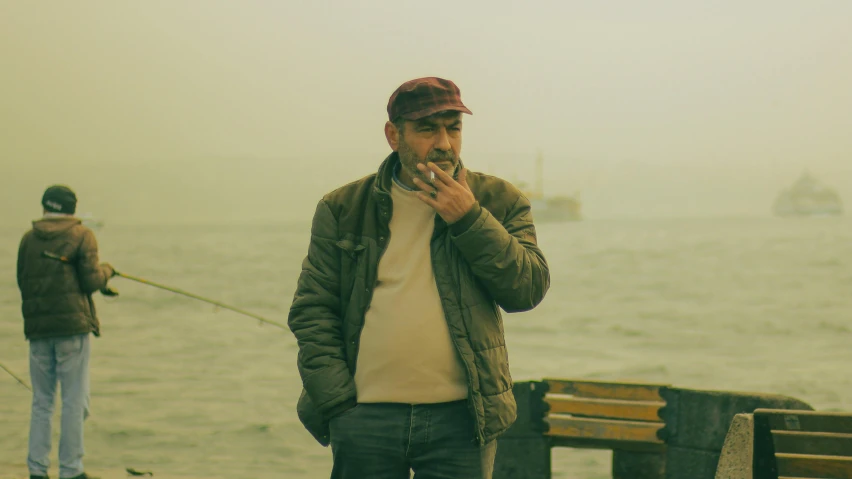 a man standing on a pier smoking a cigarette, a picture, by Elsa Bleda, pexels contest winner, hyperrealism, turkey, portrait of a old, retro haze, middle - age
