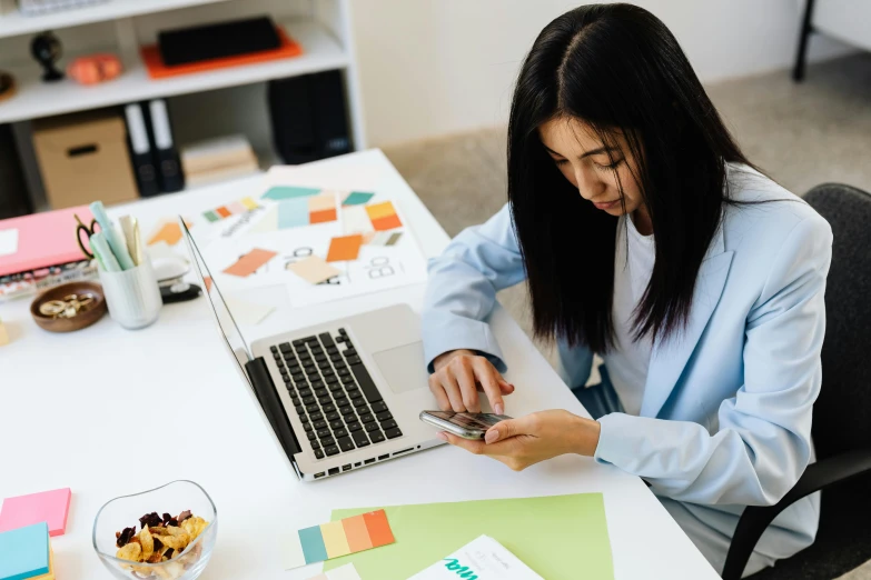 a woman sitting at a desk using a cell phone, trending on pexels, multicoloured, 9 9 designs, student, 1 2 9 7