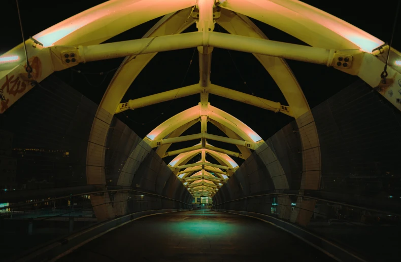 a tunnel in the middle of a city at night, inspired by Zaha Hadid, unsplash contest winner, golden curve structure, large pipes, photo taken on fujifilm superia, on a bridge