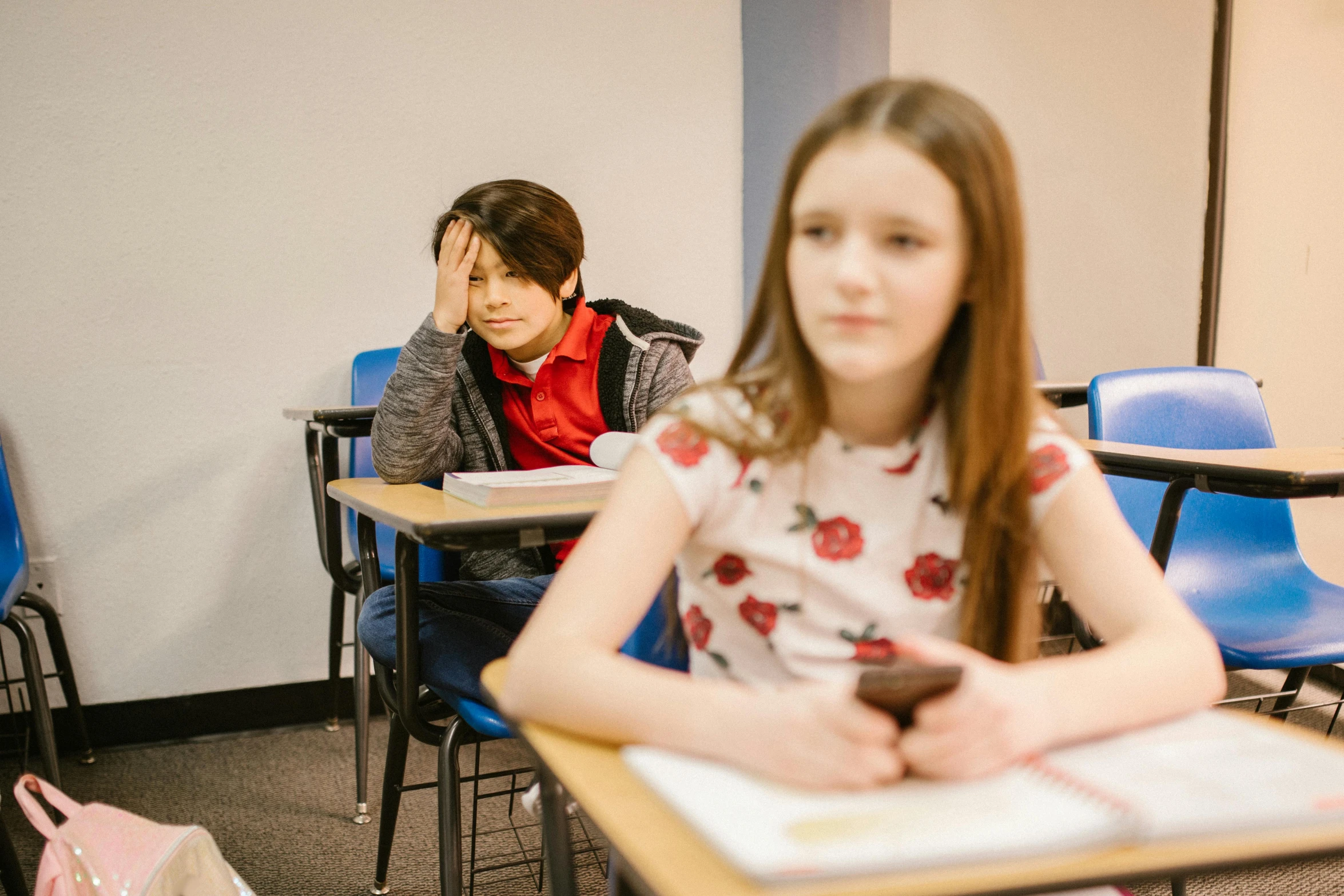 a boy and a girl sitting at desks in a classroom, trending on pexels, portrait of depressed teen, lachlan bailey, distant photo, thumbnail