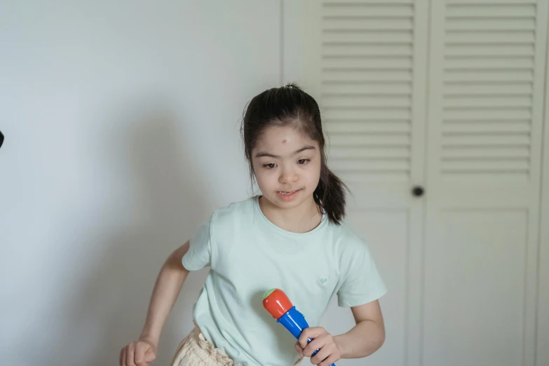 a little girl that is playing with a toy, inspired by Ruth Jên, pexels contest winner, holding a torch, standing sideways, holding microphone, asian female