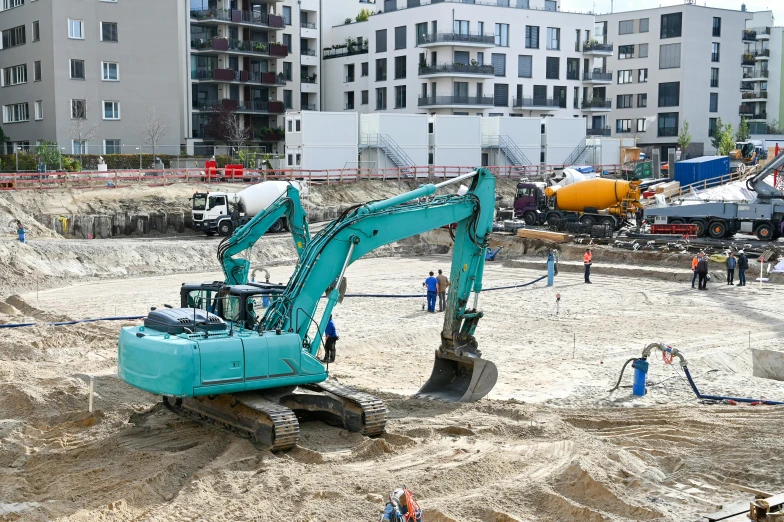 a large blue excavator sitting on top of a dirt field, by Matthias Stom, unsplash, figuration libre, urban playground, in a beachfront environment, people at work, a green