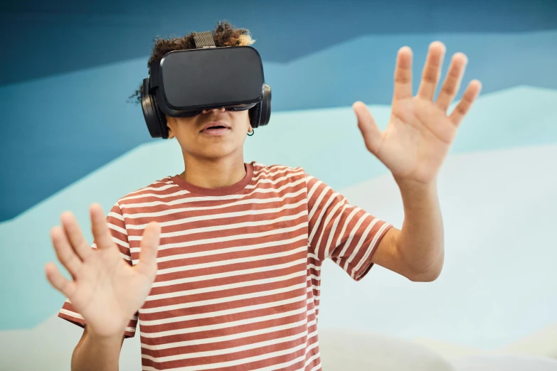 a man in a striped shirt wearing a virtual reality headset, trending on pexels, interactive art, black teenage boy, wave a hand at the camera, schools, no watermarks