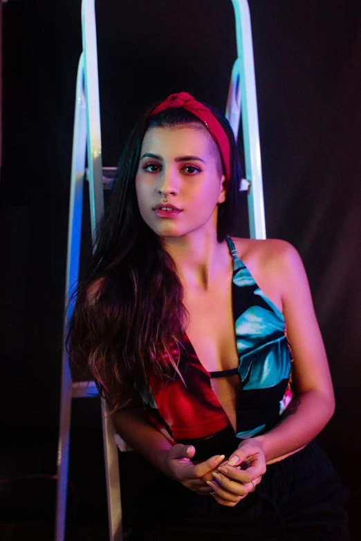 a woman standing in front of a ladder, an album cover, by Julia Pishtar, unsplash, red headband, vibrant lights, instagram model, pokimane