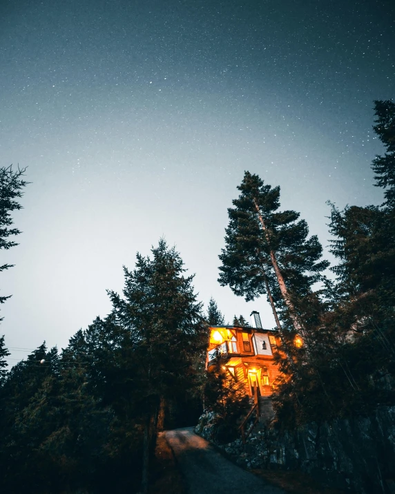 a house in the middle of a forest at night, pexels contest winner, chalet, over the tree tops, vacation photo, 🌲🌌