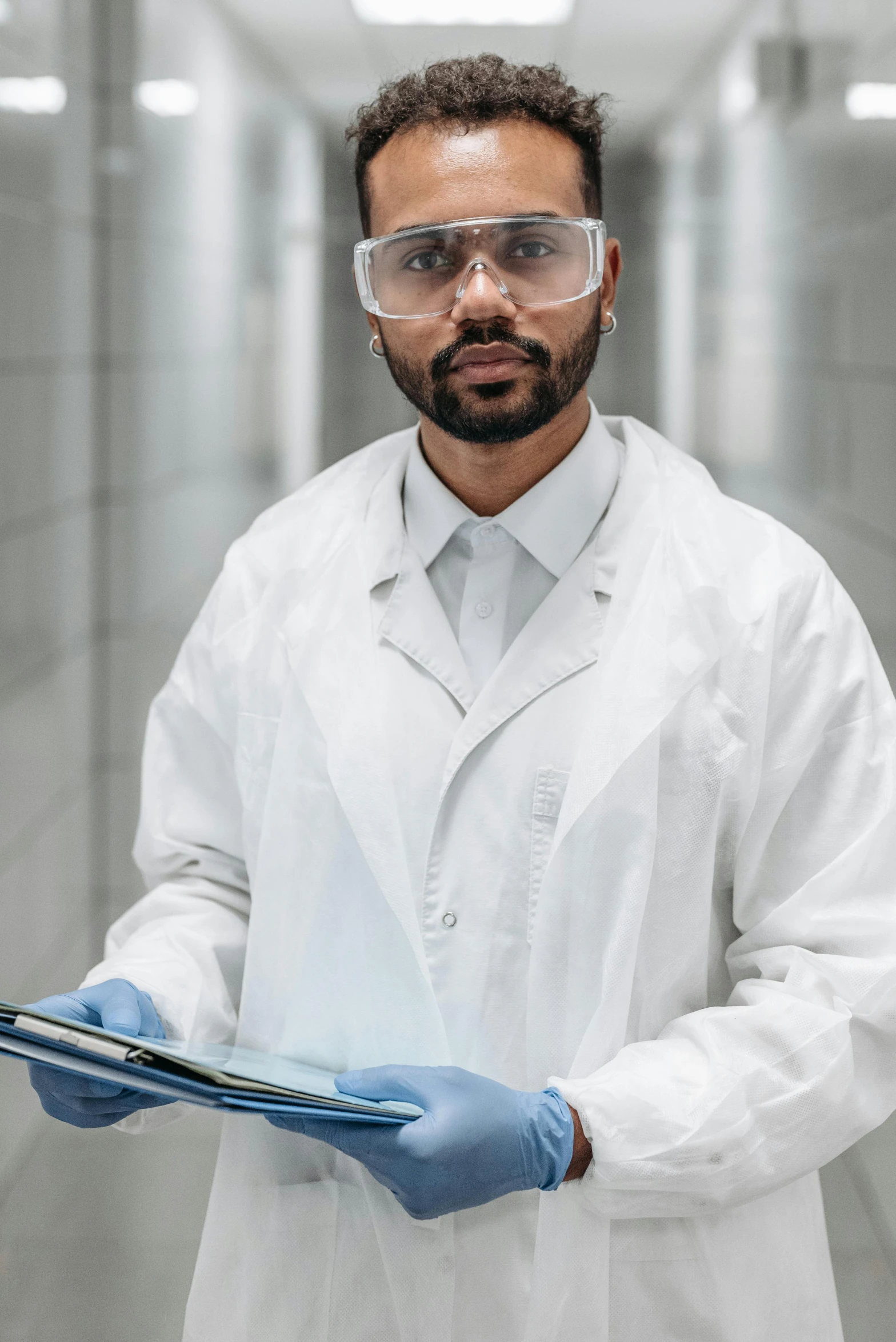 a man in a lab coat and goggles holding a clipboard, pexels contest winner, in a research facility, portrait of a male hydromancer, diverse, serious