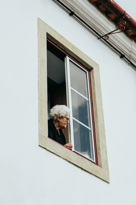 an older woman looking out of a window, by Joze Ciuha, pexels contest winner, renaissance, portugal, black windows, viewed from a distance, square