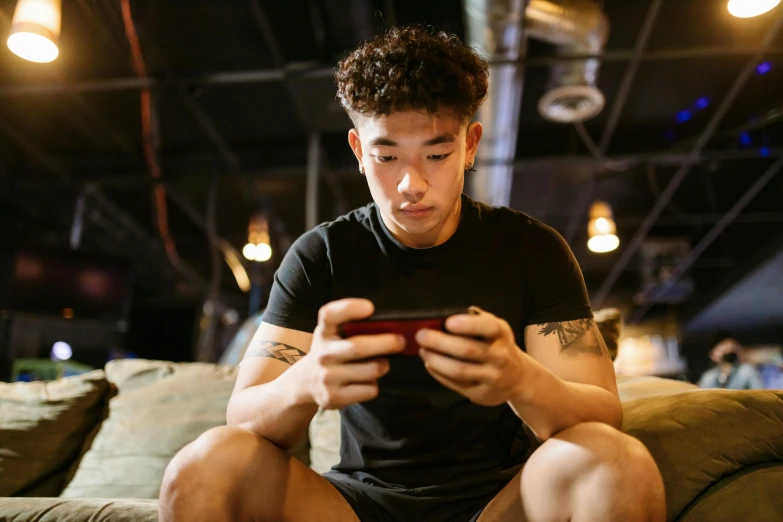 a man sitting on a couch looking at his cell phone, trending on pexels, portrait of a japanese teen, a muscular, led gaming, bao pham