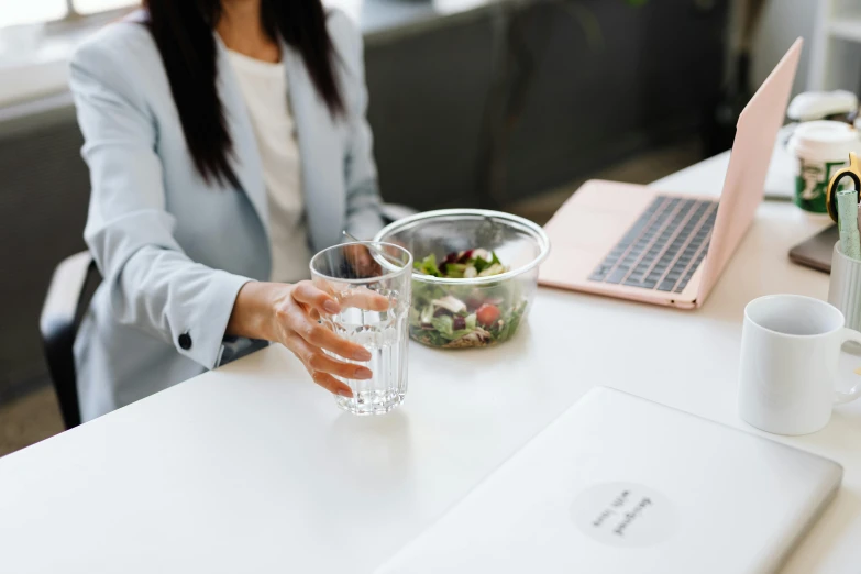 a woman sitting at a table with a glass of water, professional branding, bowl filled with food, unsplash transparent, office clothes