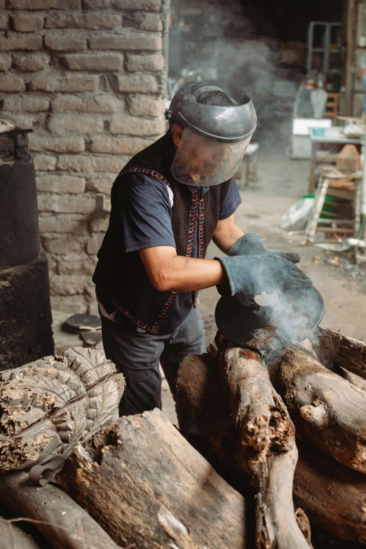 a man standing next to a pile of logs, by Alejandro Obregón, pexels contest winner, process art, wearing ornate helmet, working in the forge, in an ancient tomb, balaclava