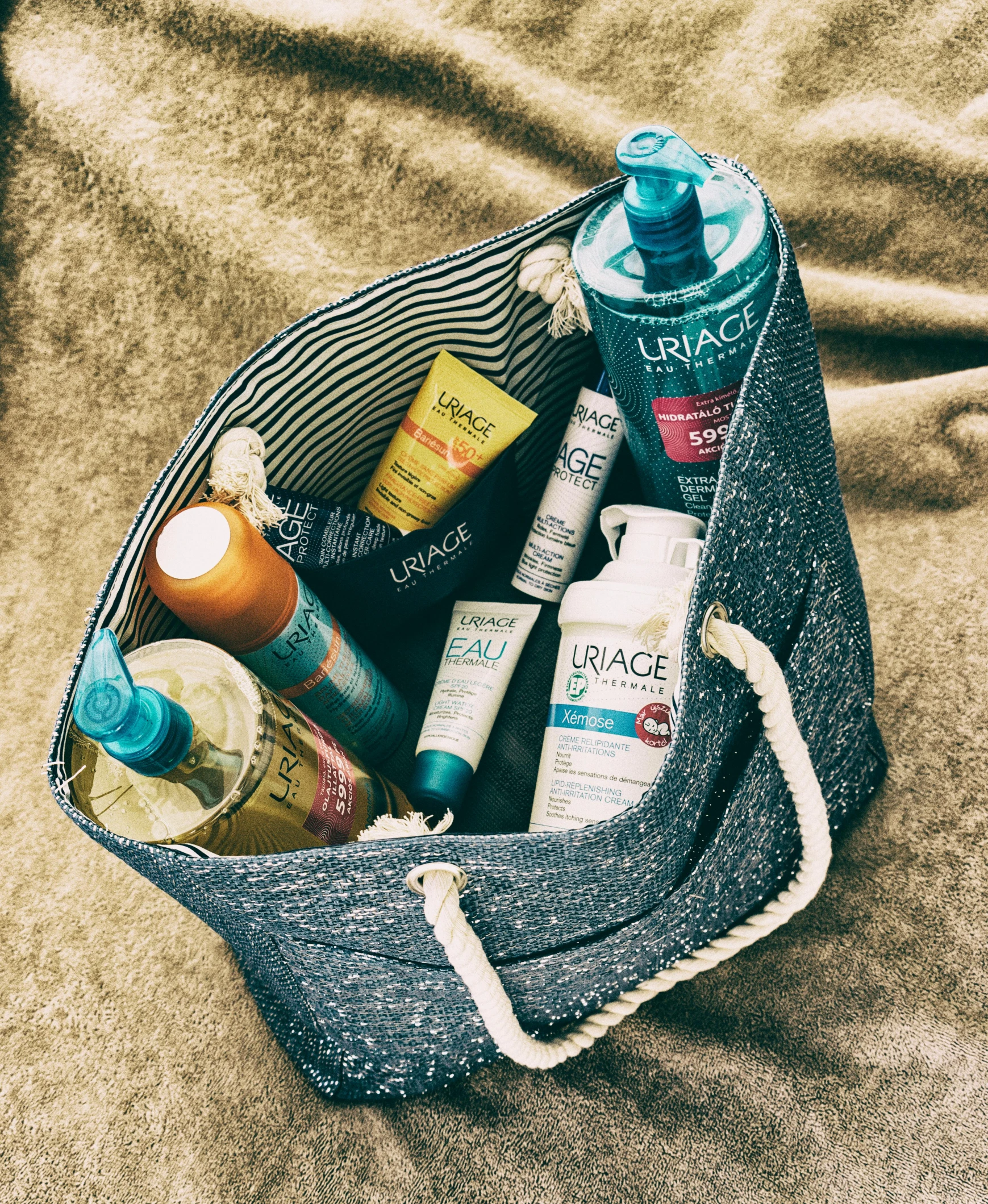 a bag filled with personal care items on top of a bed, by Lucia Peka, beach party, sunflare, textured base ; product photos, embrace