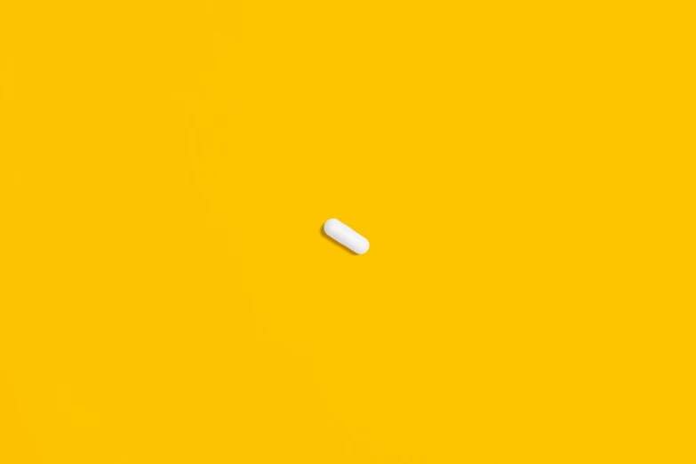 a white pill sitting on top of a yellow surface, by Gavin Hamilton, minimalism, ignant, medicine, instagram post, anton fedeev