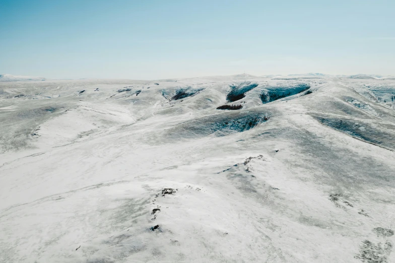 a man riding a snowboard on top of a snow covered slope, an album cover, by Jesper Knudsen, pexels contest winner, les nabis, aerial view of an ancient land, desolate glacial landscape, an expansive grassy plain, inuk