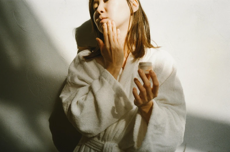 a woman in a bathrobe brushing her teeth, inspired by Elsa Bleda, trending on pexels, hyperrealism, kiko mizuhara, skincare, bare shoulders, in style of ren hang