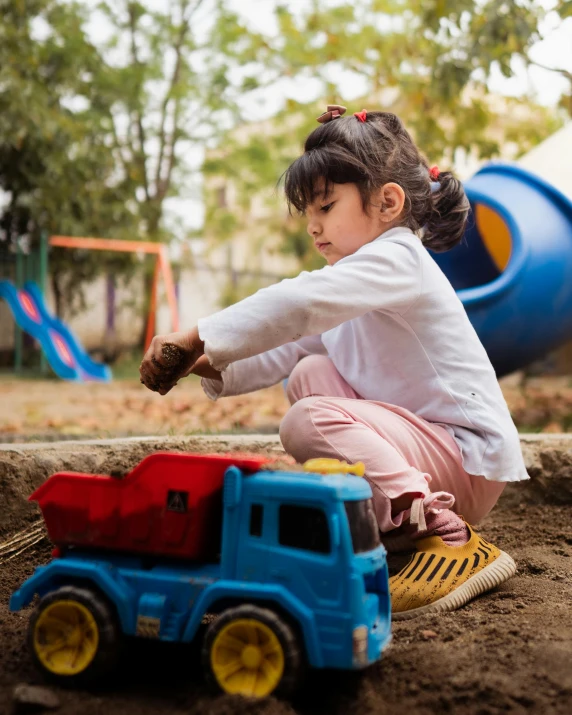 a little girl playing in the sand with a toy truck, pexels contest winner, sitting in the garden, construction, girl wearing uniform, future activist