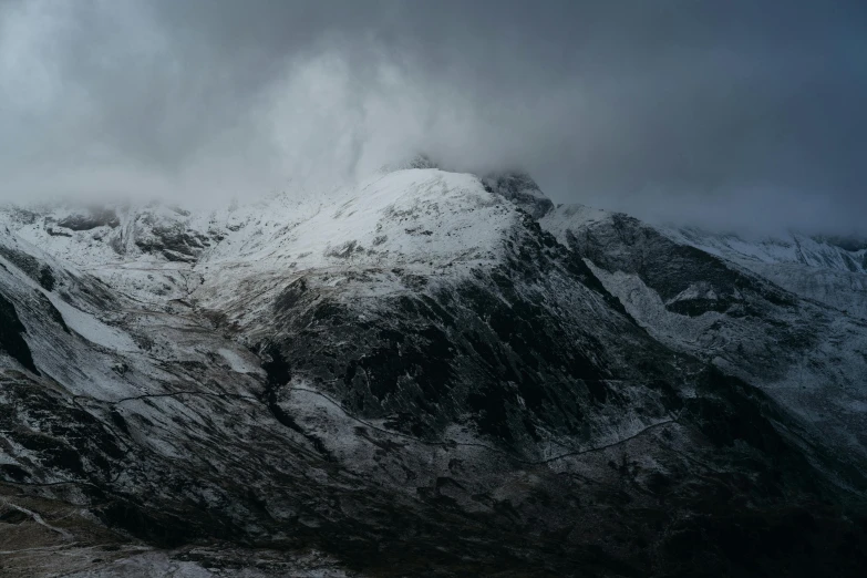 a mountain covered in snow under a cloudy sky, by Peter Churcher, pexels contest winner, hurufiyya, moody hazy lighting, wales, photo for magazine, overcast gray skies