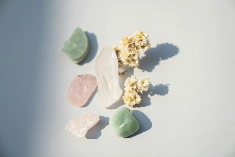 a group of stones sitting on top of a white surface, pink white and green, clear facial details, various items, high quality product image”