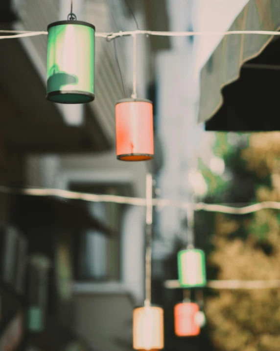 a string of lights hanging from the side of a building, colorful lanterns, desaturated, distant photo, porches