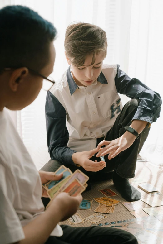 two boys sitting on the floor playing a game, by Adam Marczyński, pexels contest winner, visual art, the front of a trading card, healthcare, looking smart, mtg style