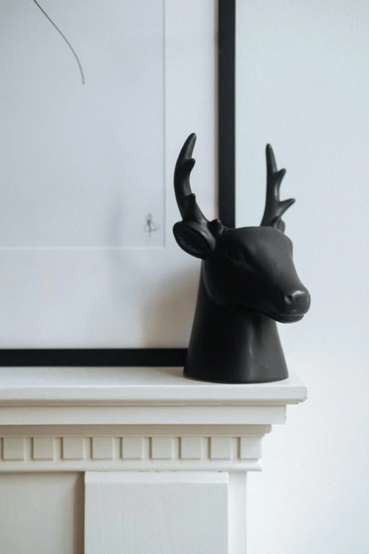 a black deer head sitting on top of a mantle, unsplash, new sculpture, all black matte product, jar on a shelf, angled shot, from side