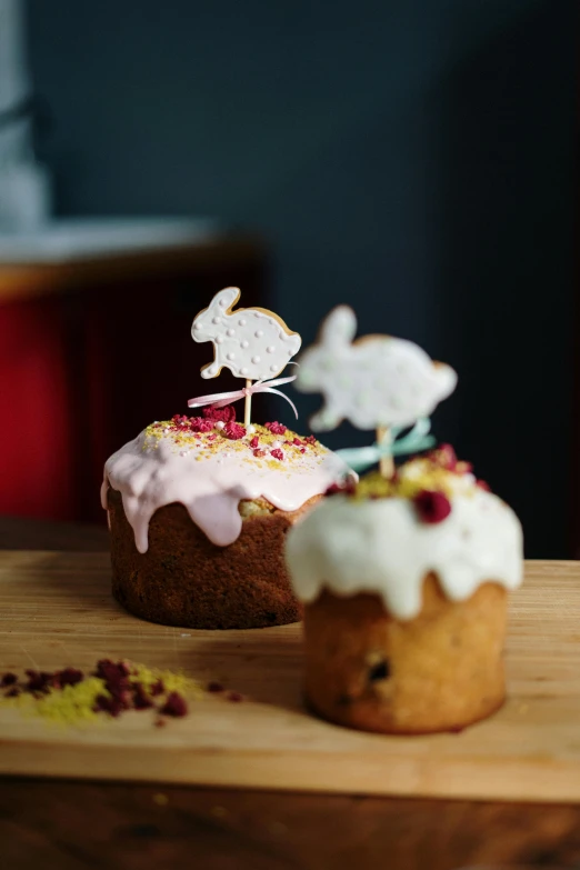 a couple of cupcakes sitting on top of a wooden table, white rabbit, dough sculpture, on a mini world, product photograph