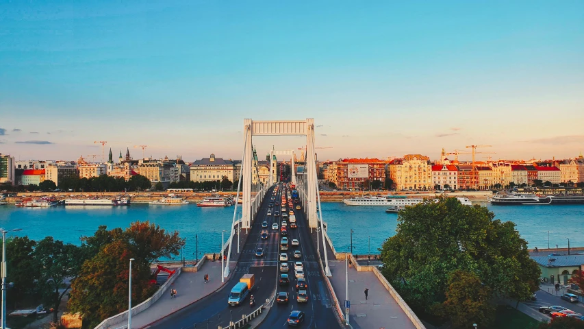 cars driving across a bridge over a river, by Matija Jama, pexels contest winner, budapest street background, sunny sky, vibrant hues, 🚿🗝📝