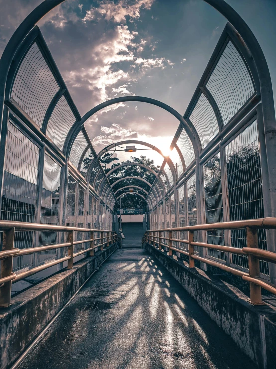 a walkway leading to a train station under a cloudy sky, a picture, unsplash contest winner, light and space, metallic bridge, sakimichan hdri, natural prison light, today\'s featured photograph 4k