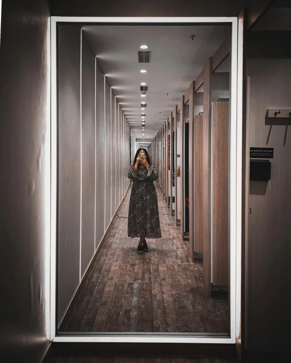 a woman standing in the middle of a hallway, inspired by Cheng Jiasui, pexels contest winner, capsule hotel, queer woman, theater dressing room, wooden toilets