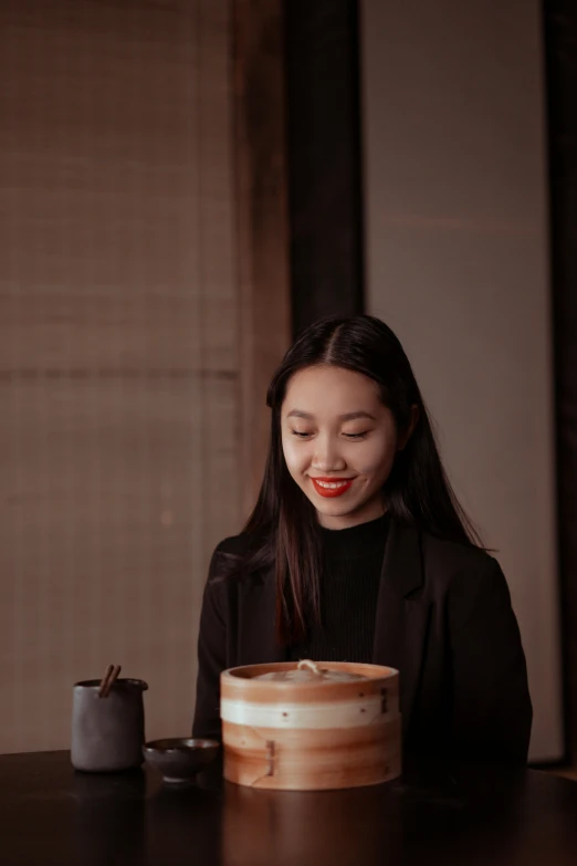 a woman sitting at a table with a cake in front of her, inspired by Qian Du, trending on unsplash, mingei, carrying a tray, low quality photo, soup, close up portrait shot