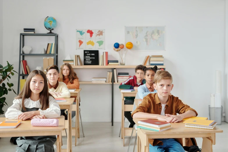 a group of children sitting at desks in a classroom, trending on pexels, avatar image, fan favorite, academic clothing, full product shot