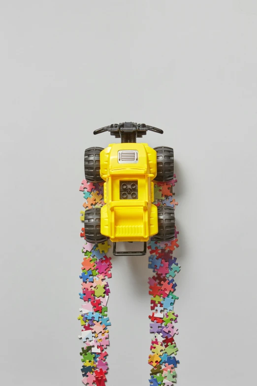 a toy truck made out of confetti sprinkles, a jigsaw puzzle, colors: yellow, hasselblade wide shot, climber, zoomed out