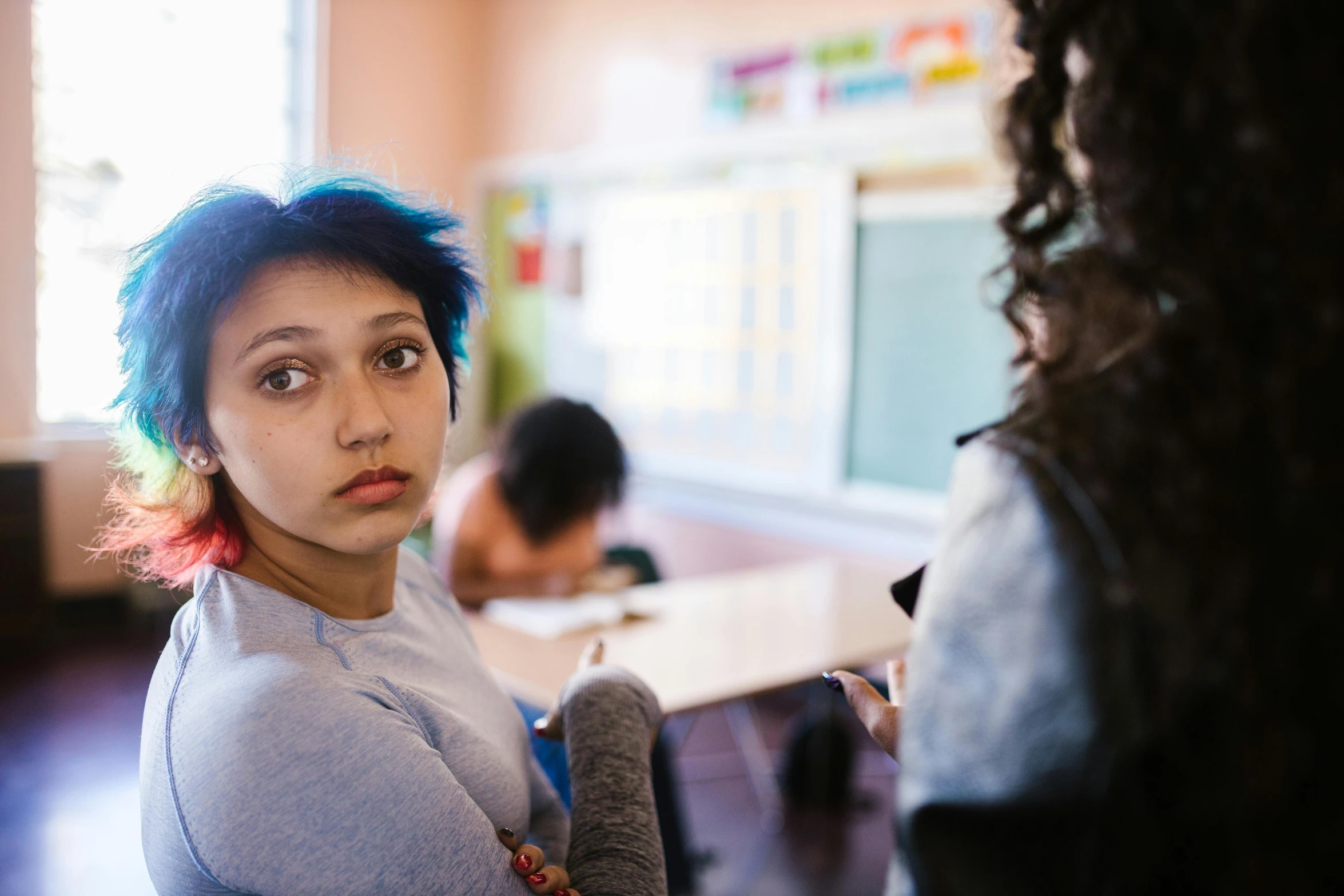 a woman with blue hair sitting in a classroom, trending on tumblr, danube school, woman holding another woman, concerned expression, shot with sony alpha 1 camera, teenage girl