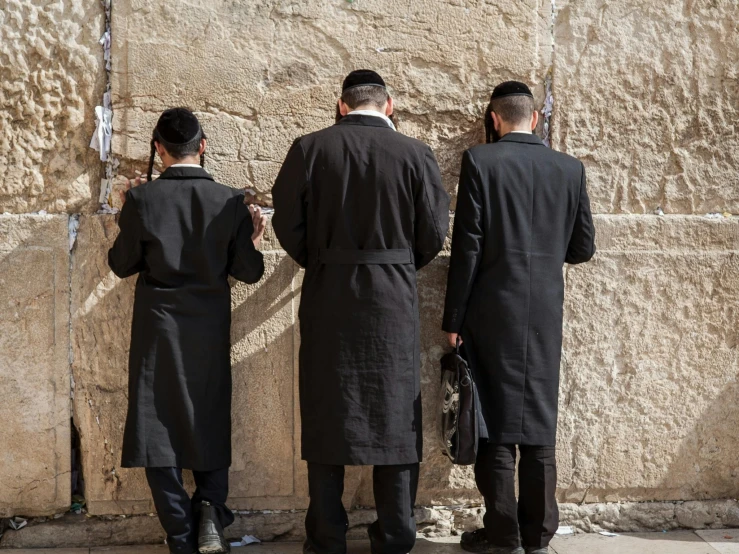 a group of men standing in front of a stone wall, trending on unsplash, les nabis, hebrew, religious robes, as well as scratches, 3 - piece