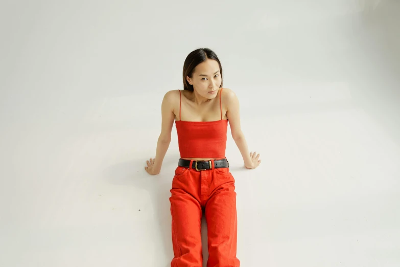 a woman sitting on top of a white floor, an album cover, inspired by Fei Danxu, pexels contest winner, wearing red tank top, wearing overalls, visible stomach, avatar for website