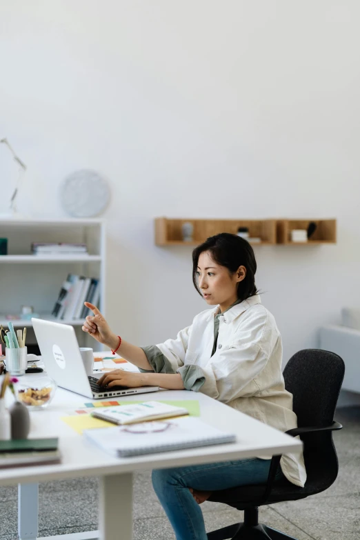 a woman sitting at a desk with a laptop, inspired by Fei Danxu, studio kyoto, open office, documentation, half - turn